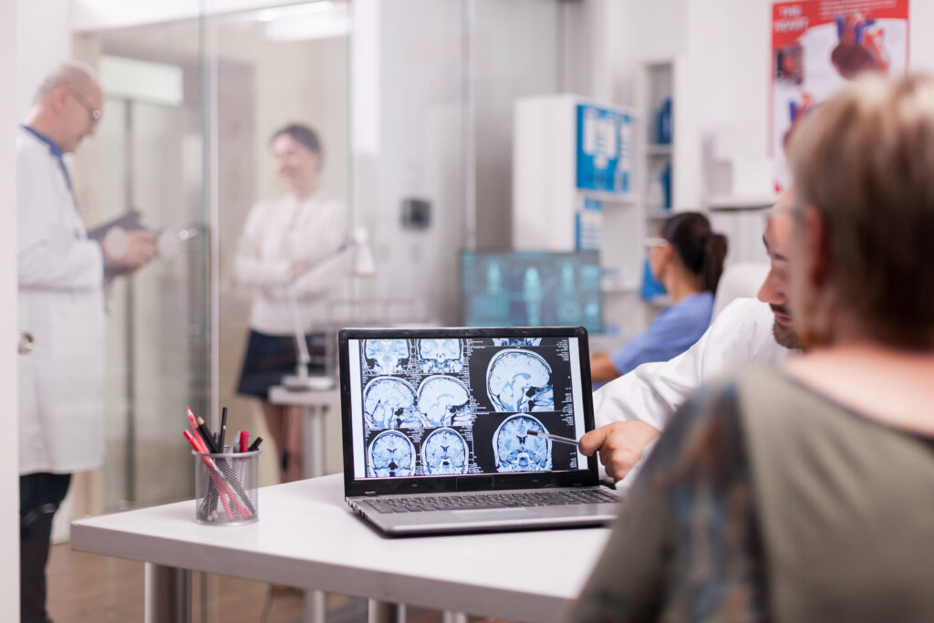 A man and woman examine a computer screen while discussing headache specialist information.