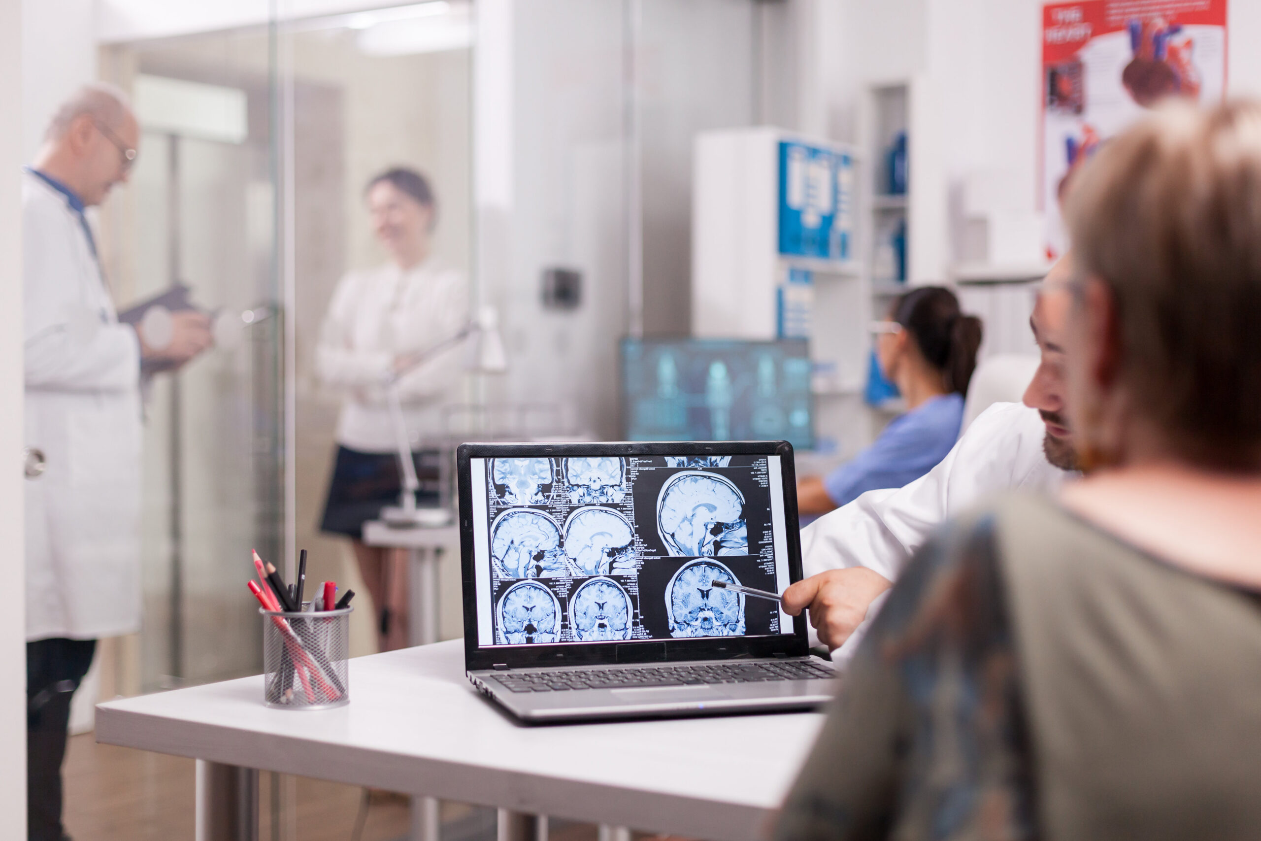 A man and woman examine a computer screen while discussing headache specialist information.